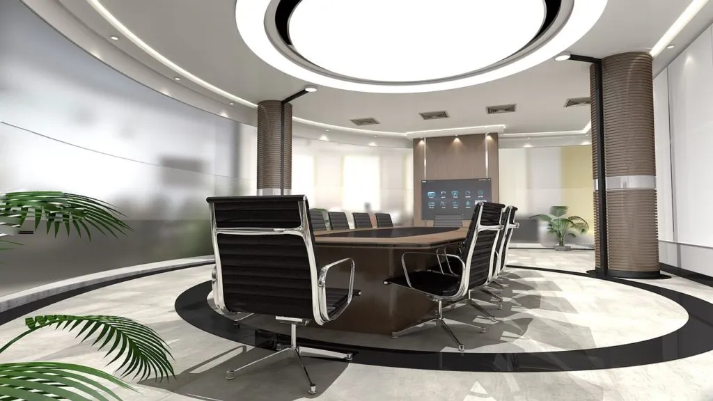Empty modern conference room with an oval table, black chairs and a screen on the wall.