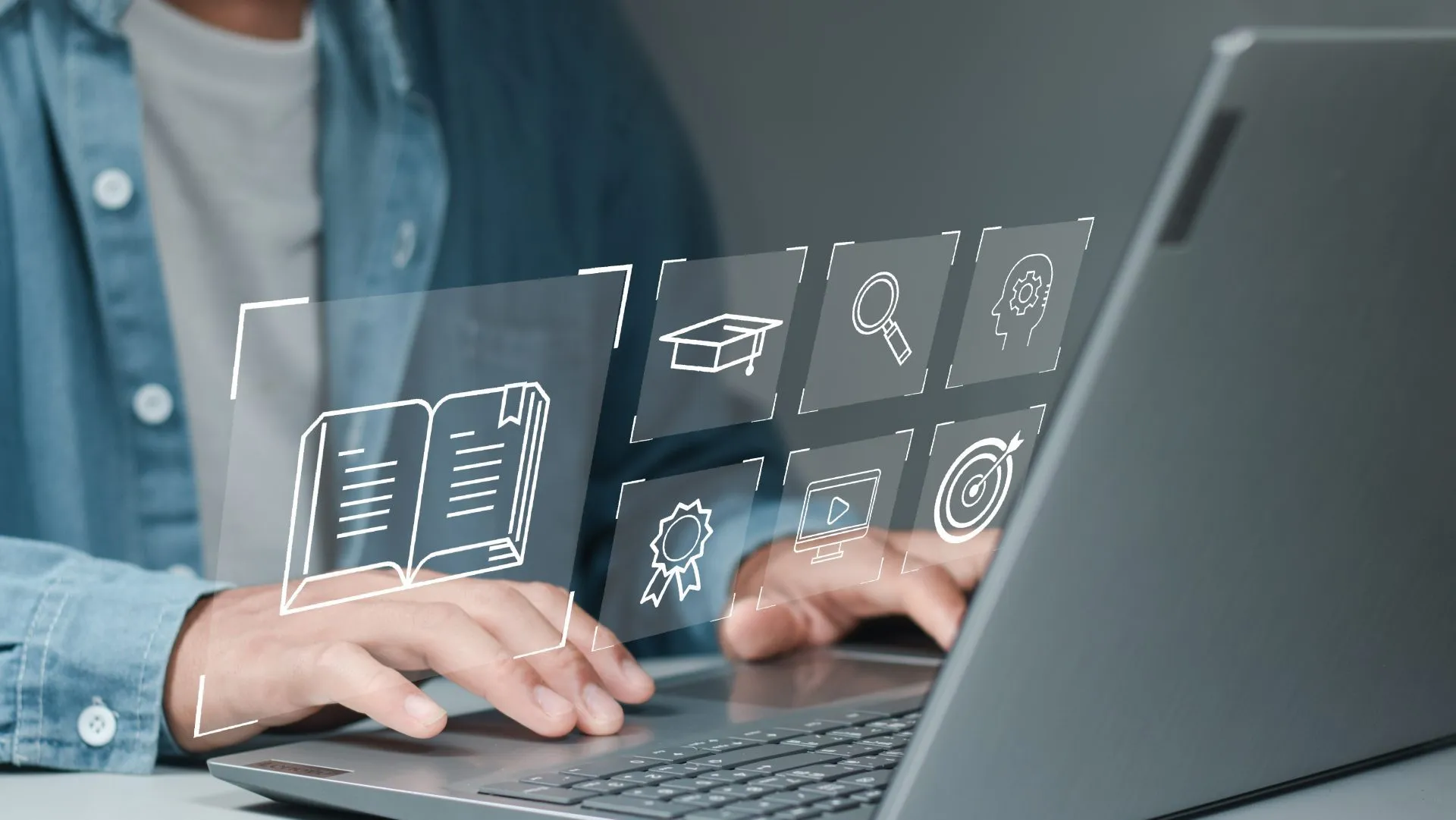 Person typing on a laptop with floating e-learning icons: book, graduation cap, video player, target