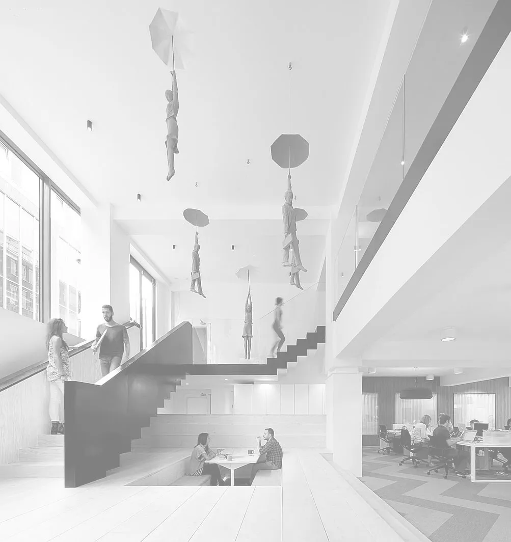 Helles, offenes Bürofoyer mit Treppe; von der Decke hängen Figuren, die an Schirmen schweben.