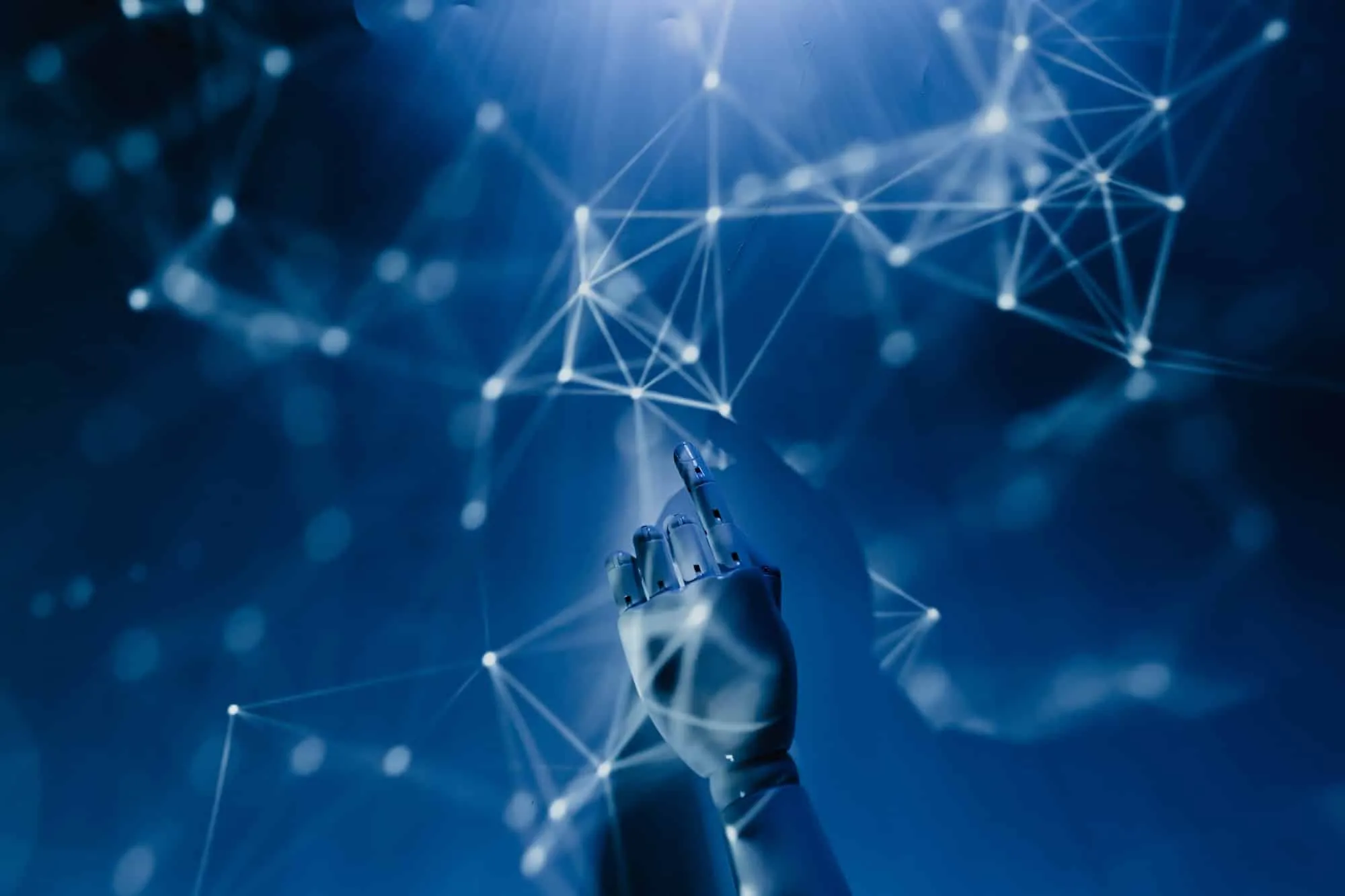 White robotic hand reaching up to touch a glowing network of connected nodes on deep blue
