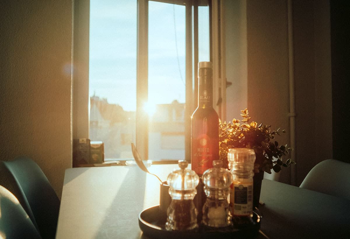 Abendsonne fällt auf einen Tisch mit einer Flasche, Gewürzmühlen und einer Pflanze.